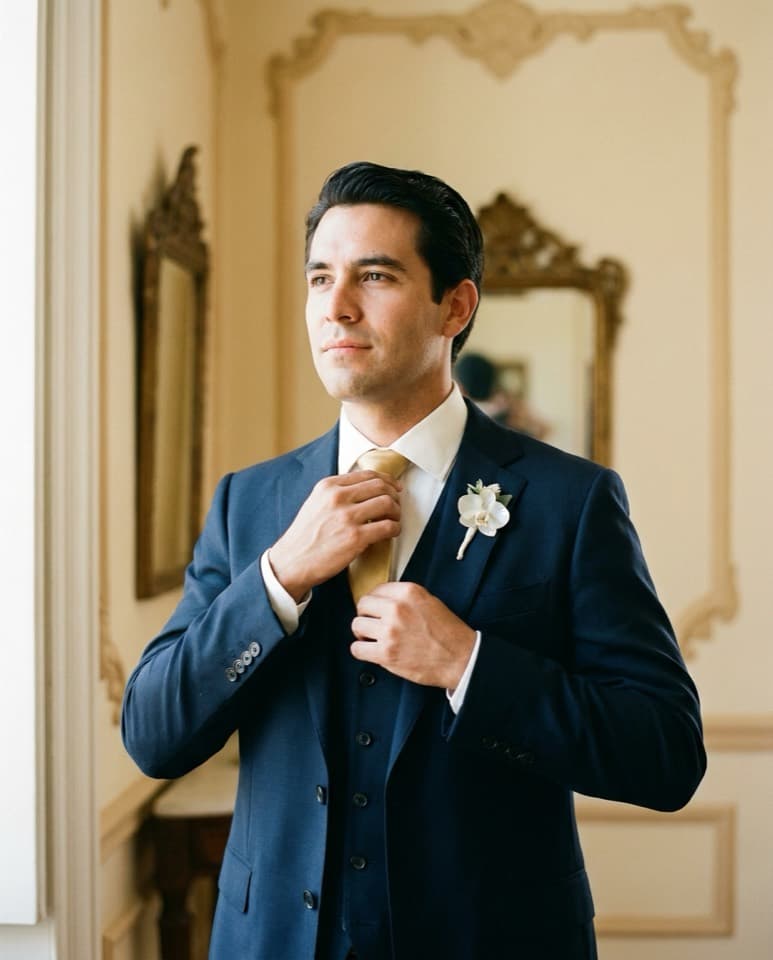 Modelo en traje formal navy ajustándose la corbata